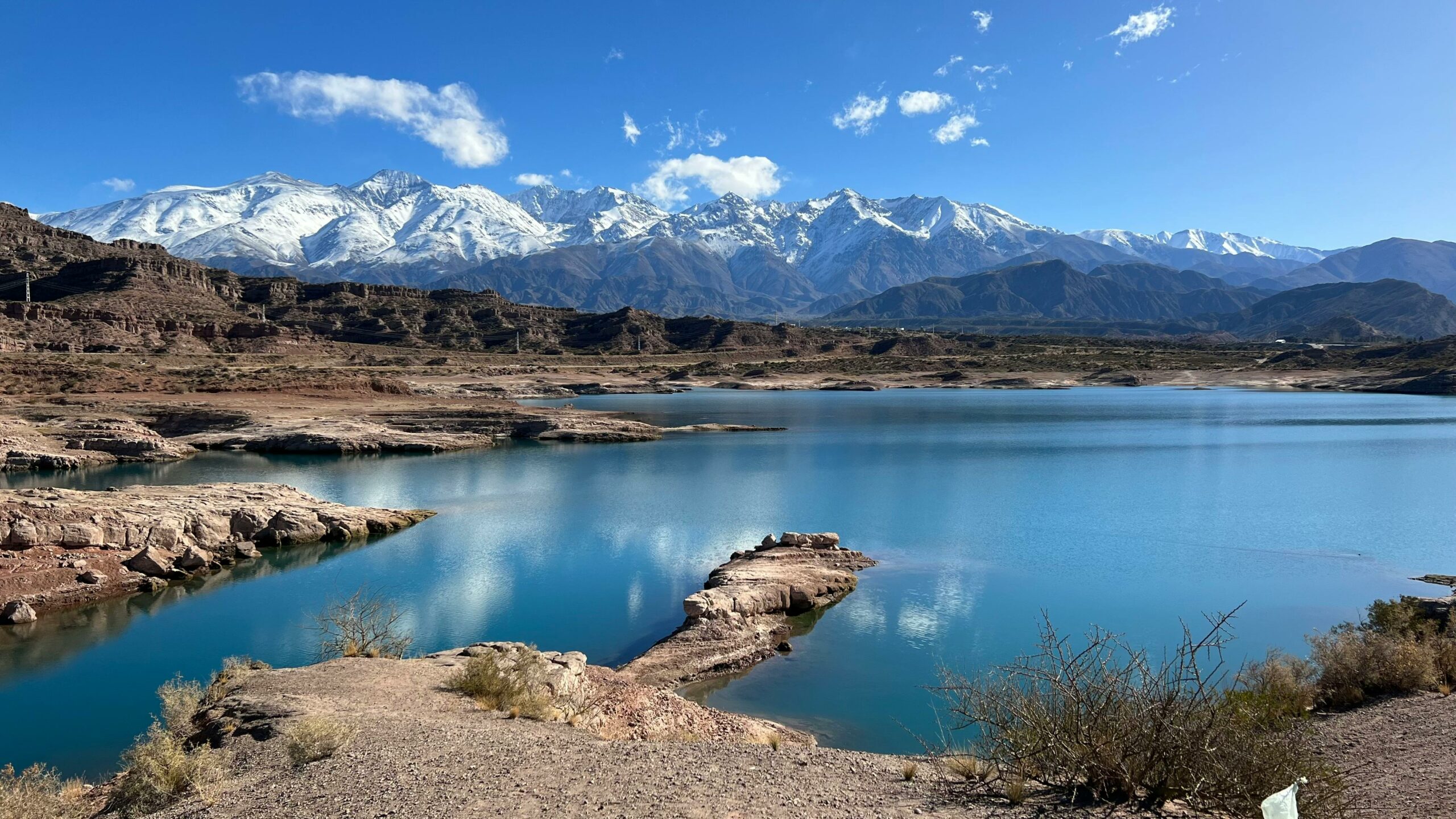 Breathtaking view of snow-capped Andes mountains reflecting in Potrerillos Lake, Mendoza.